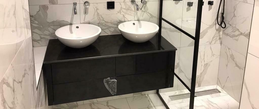 Afgewerkte badkamer met marmerlook tegels en dubbele waskom