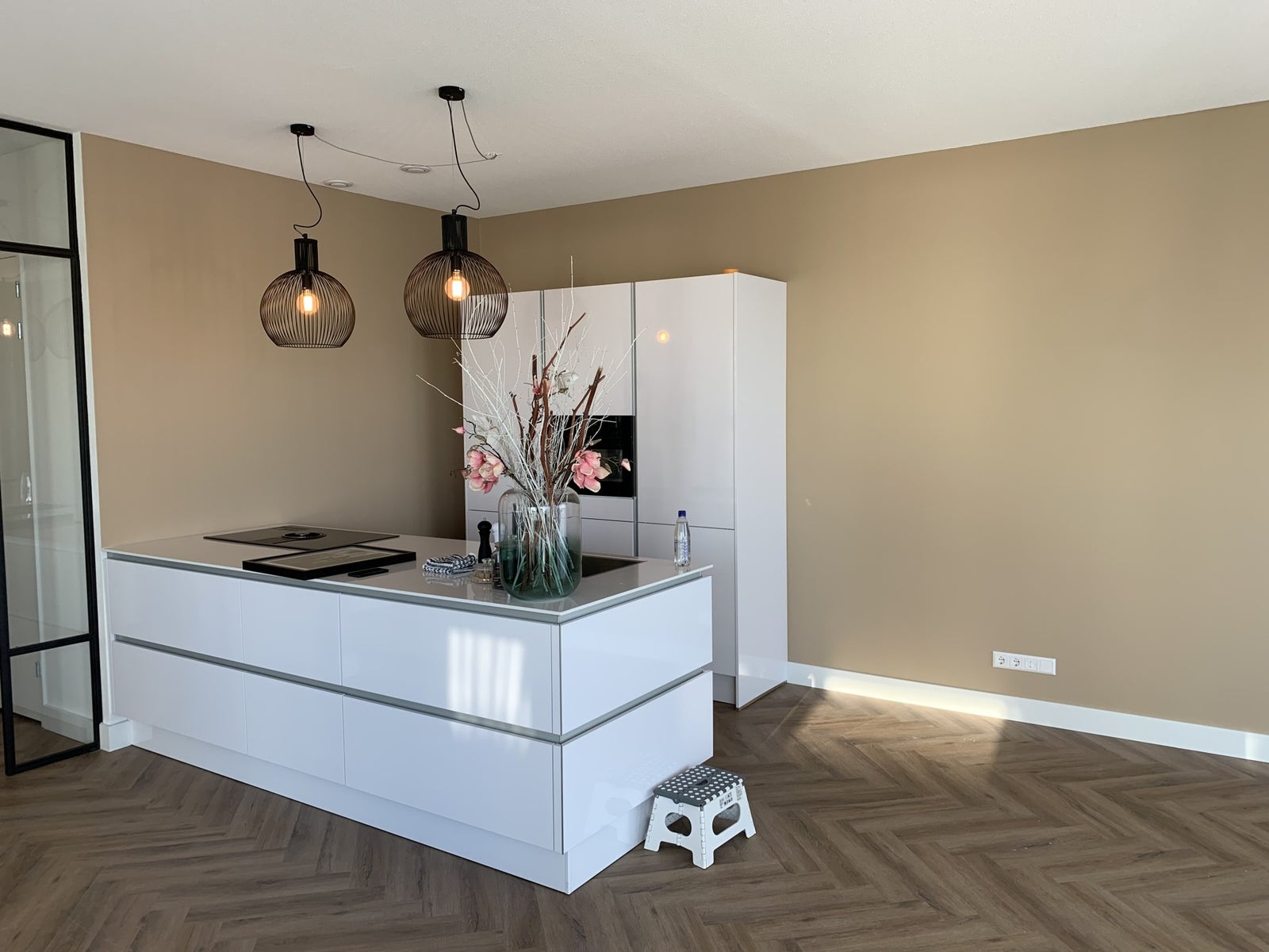 Open keuken met kookeiland, beige wanden en visgraatvloer